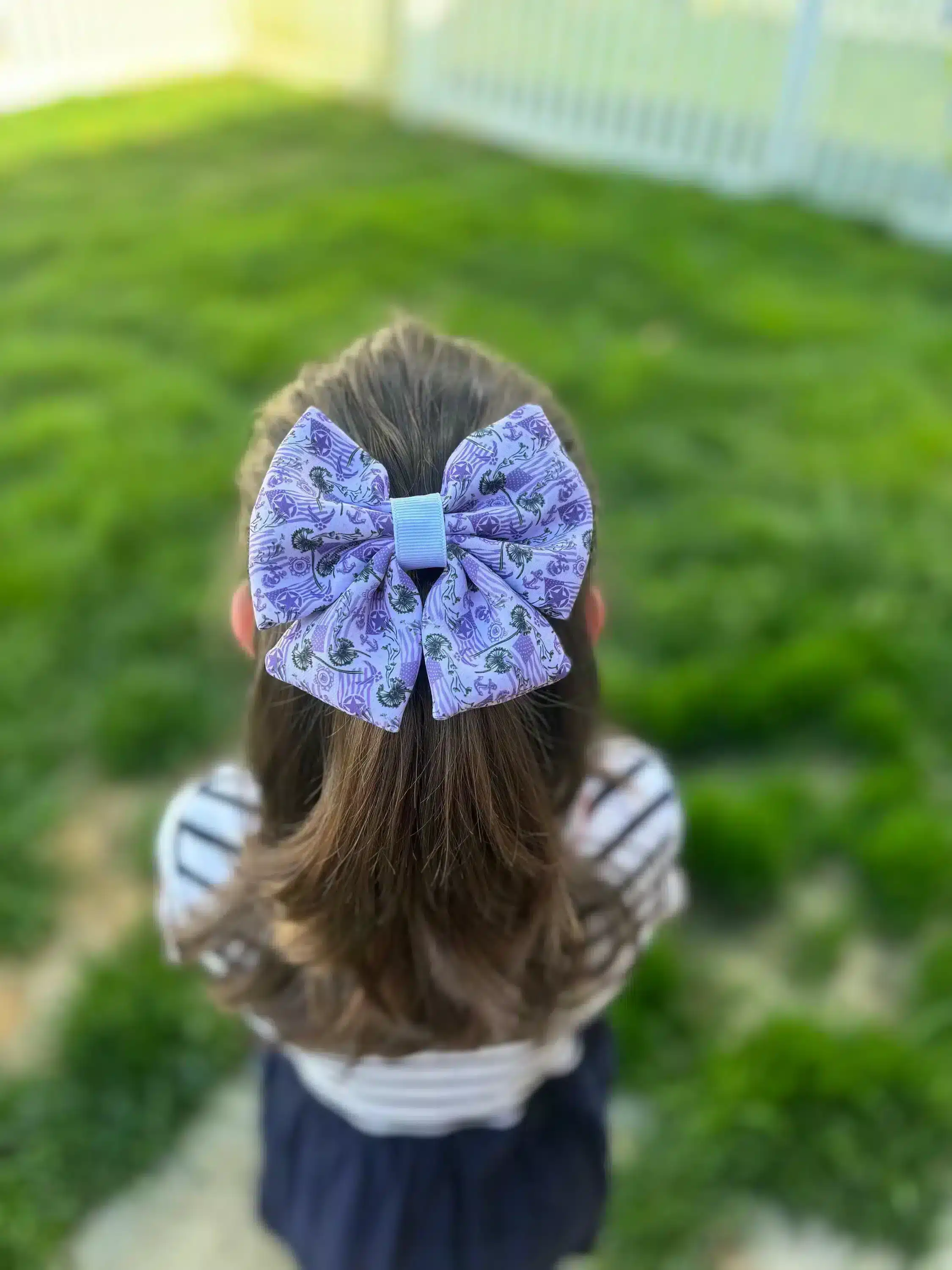 Image of a girl wearing a US Flag and Dandelions hair bow in her hair, showing the back view with a clear display of the bow's design.