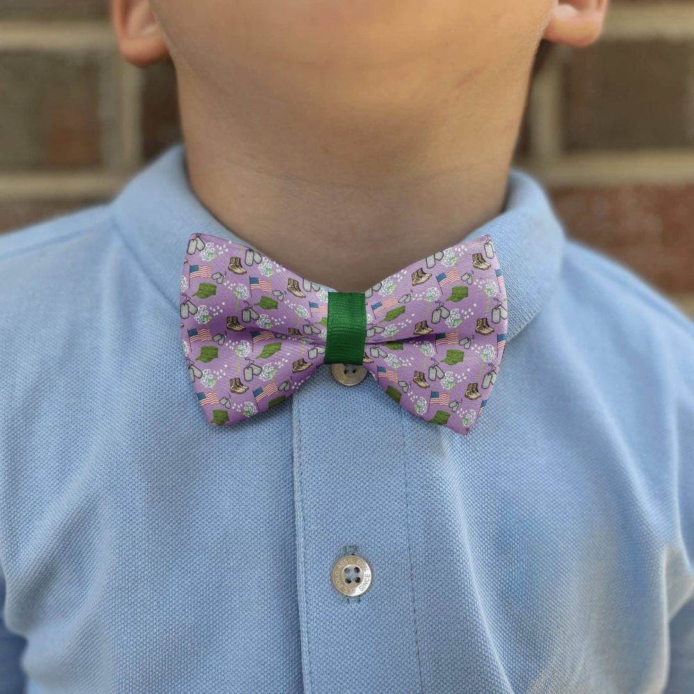 Child wearing purple patterned bow tie and blue shirt.