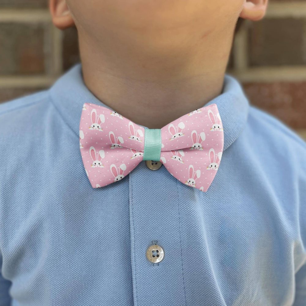 Child wearing bunny-patterned bow tie on blue shirt.