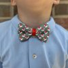 Child wearing Santa-themed bow tie, blue shirt.