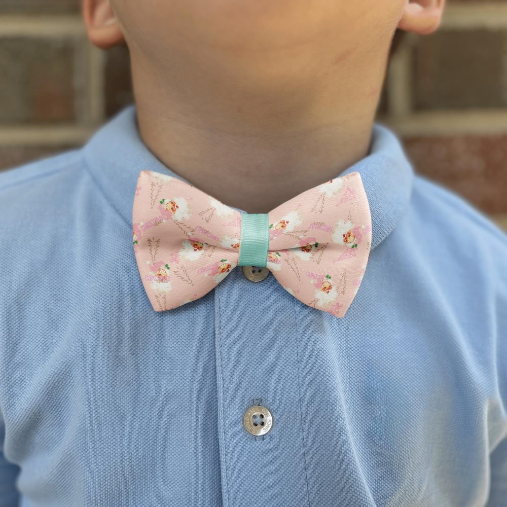 Child wearing pink floral bow tie and blue shirt.