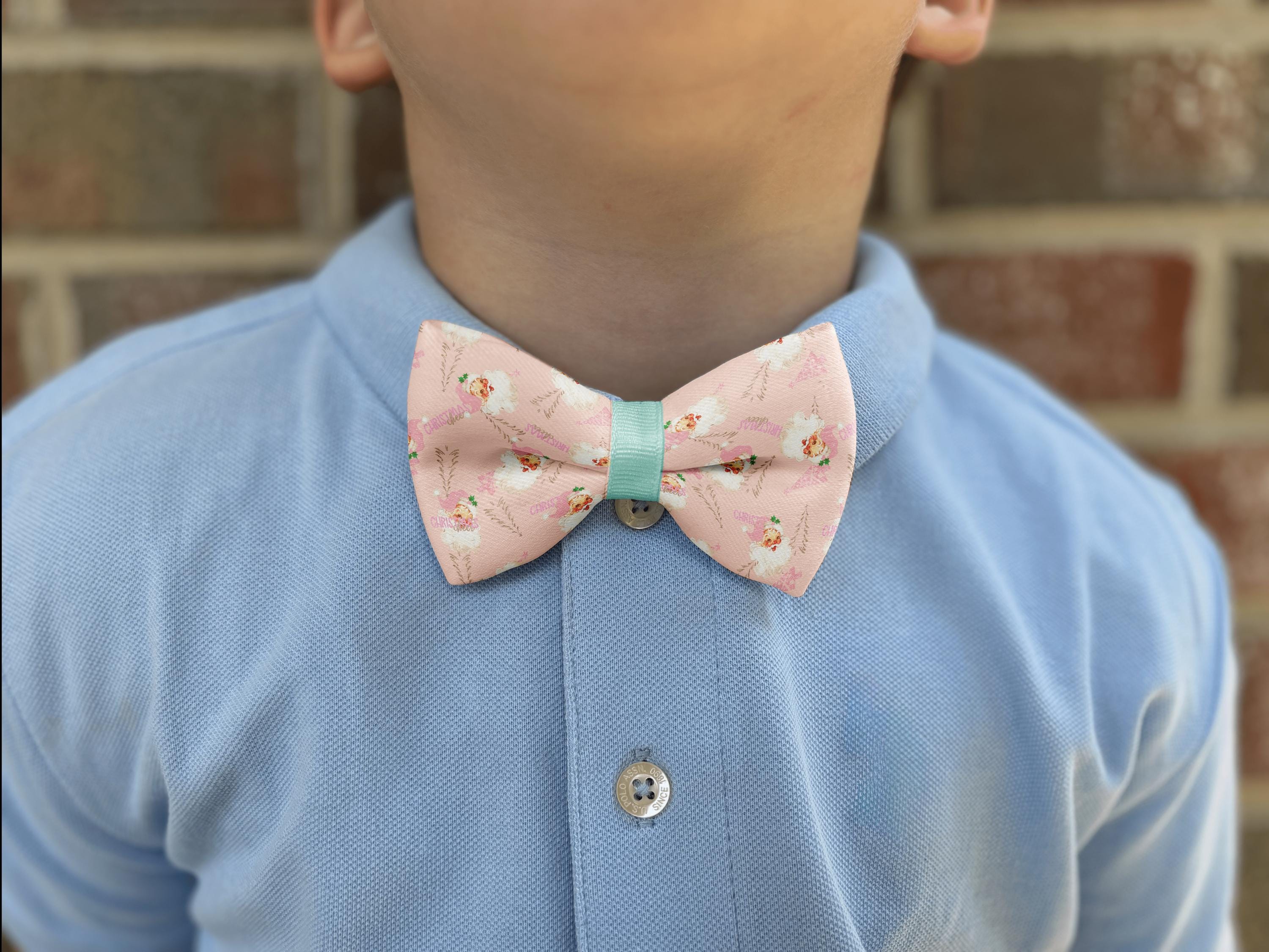 Child wearing pink floral bow tie and blue shirt.