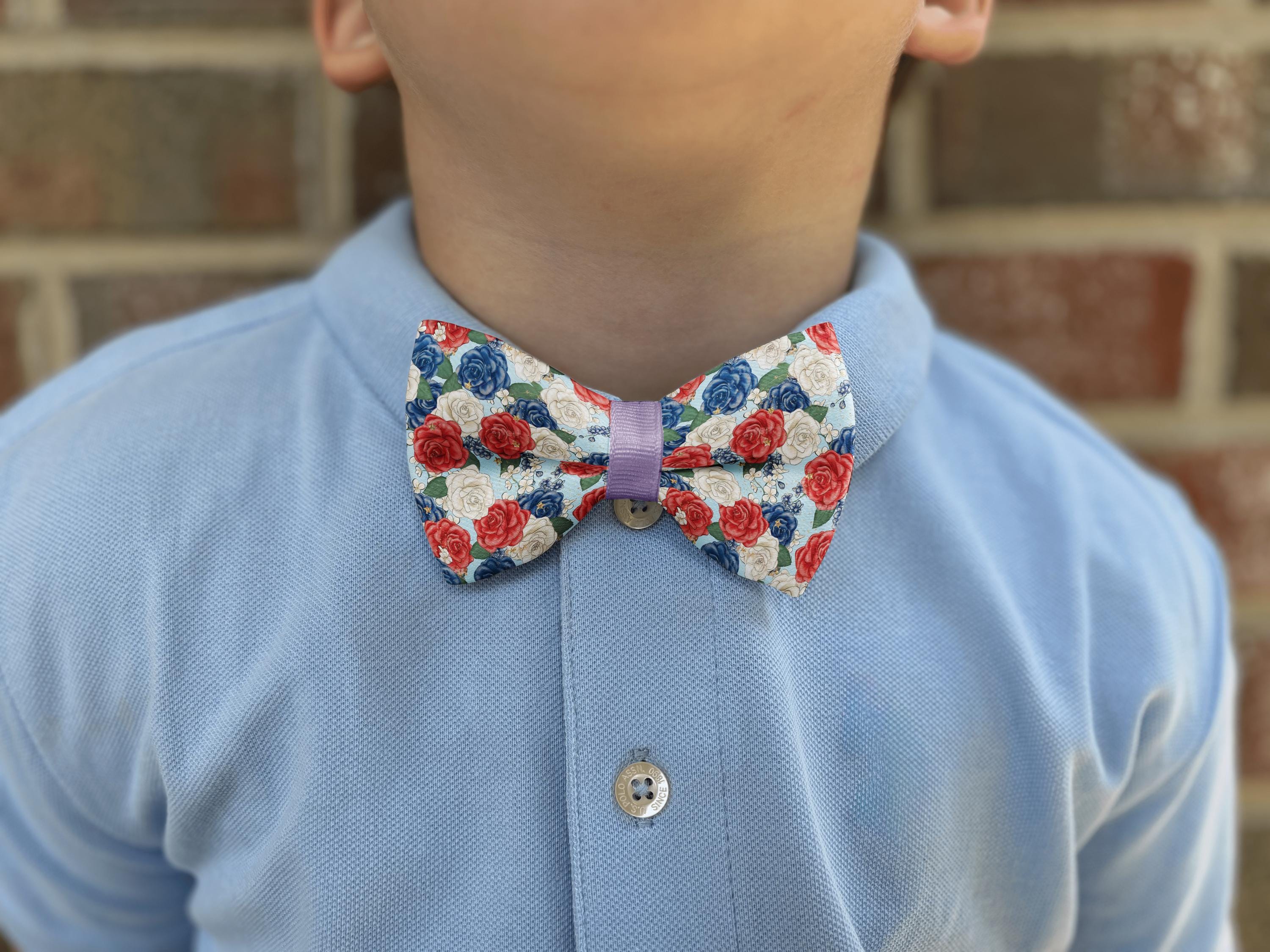 Child wearing floral bow tie with blue shirt.