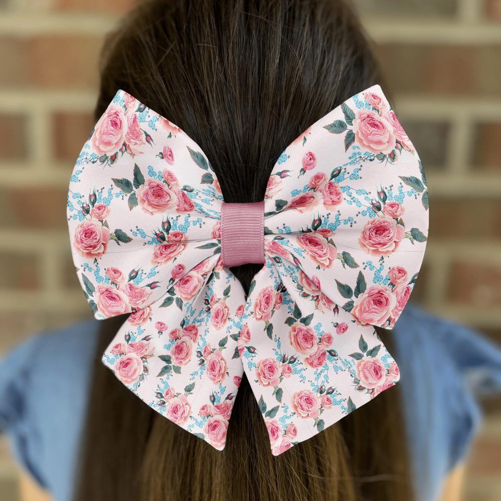 Floral bow on brown-haired girl against brick wall.